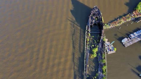Aerial,-drone-top-down-video-footage-of-a-dilapidated,-rotting-ship-on-the-Hudson-River-during-summer