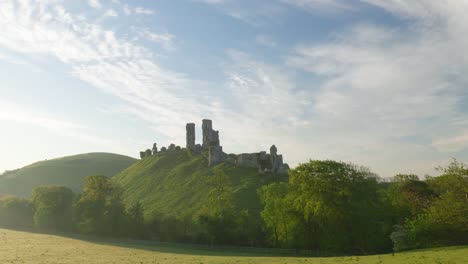 Corfe-Castle-bathed-in-a-summer's-morning-sunrise,-slow-panning-shot