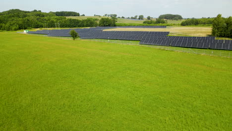 Solar-Power-Farm-on-Green-Fields-From-High-angle-of-view-in-Zielenica,-Poland-Aerial-drone-fly-over