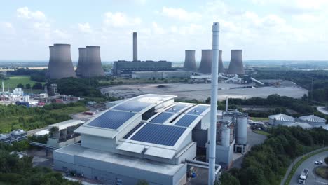 Clean-solar-rooftop-installation-on-modern-office-building-aerial-view-with-coal-power-station-in-background-slow-descend