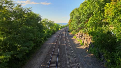 Aerial-drone-footage-of-the-metro-north-Hudson-Line-train-tracks-during-summer-next-to-the-Hudson-river-between-beacon-and-cold-spring,-new-york,-usa