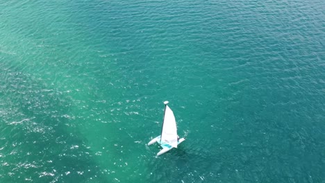 A-aerial-view-of-a-small-sailboat-in-the-blue-of-the-Caribbean-waters-on-a-sunny-day
