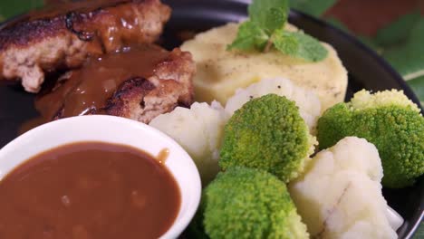 A-Delicious-Meal-Served-on-a-Plate-with-burger-patties-and-Vegetables-with-Brown-Gravy-Sauce