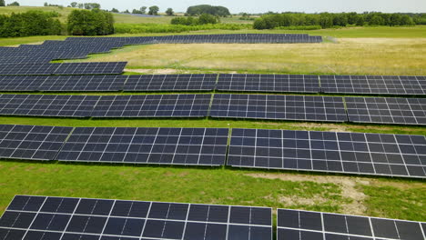 Solarkraftwerkspanels-Aus-Nächster-Nähe-Mitten-Auf-Der-Grünen-Wiese,-Luftüberführung-Polen-Mit-Niedrigem-Winkel,-Geringe-Höhe