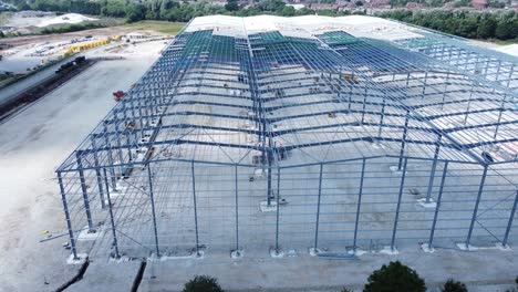 Construction-industry-metal-iron-girder-warehouse-framework-construction-site-aerial-view-rise-up-tilt-follow