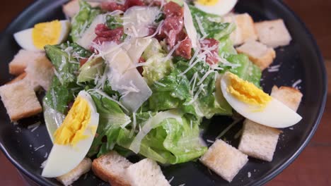 Ein-Köstlicher-Frischer-Gesunder-Caesar-salat,-Der-Sich-Auf-Einem-Schwarzen-Teller-Mit-Nahaufnahme-Dreht