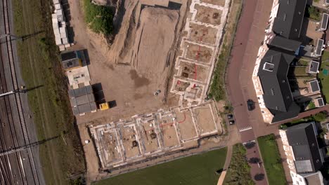 Top-down-descending-aerial-view-of-Ubuntuplein-construction-site-in-urban-development-real-estate-investment-project-revealing-wider-new-Noorderhaven-neighbourhood
