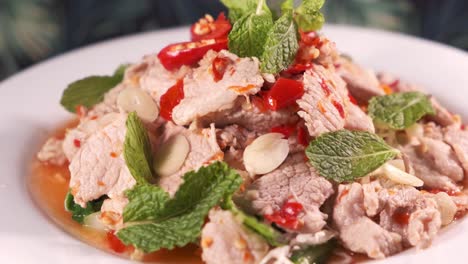 Authentic-Thai-Spicy-Sliced-Pork-salad-with-Red-Chilies-Close-Up-Rotating-on-White-Plate
