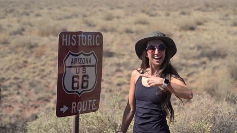 Mujer-Joven-Posando-Junto-A-La-Histórica-Ruta-66-Firmar-En-Arizona-Usa,-Fotograma-Completo