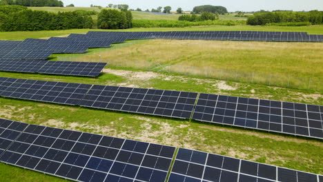 Low-angle-flight-over-modern-solar-panel-cells-installed-on-green-countryside---Renewable-and-sustainable-ecosystem-outdoors
