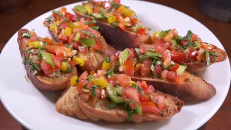 Delicious-Bruschetta-Decorated-with-Tasty-Topping-on-a-White-Spinning-Plate-Close-Up-Shot