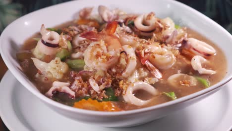 Authentische-Thailändische-Suppe-Mit-Köstlichen-Gewürzen-Und-Meeresfrüchten-In-Einer-Weißen-Schüssel,-Die-Sich-Aus-Nächster-Nähe-Dreht