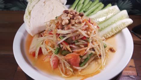 Authentische-Thailändische-Küche,-Somtam,-Papaya-Salat-Mit-Süß-saurer-Sauce,-Frisch-Zubereitet-Auf-Einem-Weißen-Drehteller-Aus-Nächster-Nähe