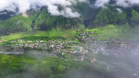 Aerial:-Mestia-highland-town,-view-through-clouds-in-Caucasus-Mountains,-Georgia