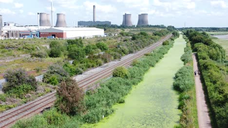 Green-algae-covered-canal-waterway-leading-to-power-station-industry-aerial-drone-view-rising-shot