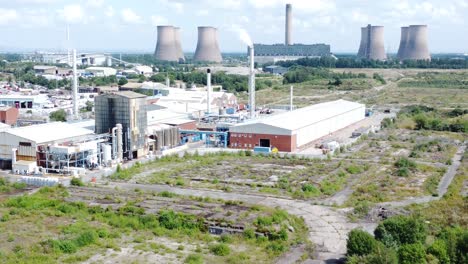 Industrial-warehouse-power-plant-refinery-buildings-under-smokestack-wasteland-aerial-view-descending-orbit-left