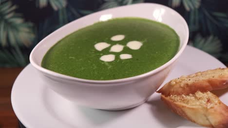 A-Bowl-of-Green-spinach-Soup-with-Sliced-Garlic-Bread-Rotating-with-Close-Up-Shot