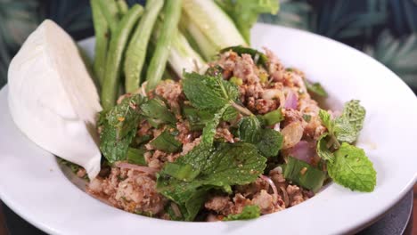 Authentic-Thai-Larb-Moo-with-Mint-and-Spices-Freshly-Cooked-Rotating-on-a-White-Plate-Close-Up