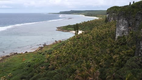 Aerial-view-of-Pacific-Ocean-and-green-hillside-sloping-to-beach-on-Maré-Island