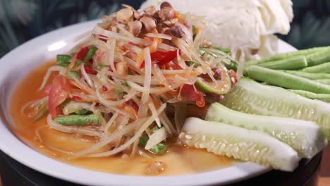 Authentic-Thai-Cuisine,-Somtam,-papaya-salad-with-Sweet-and-Sour-Sauce-Freshly-Made-on-a-White-Spinning-Plate-Close-Up