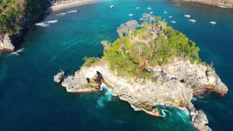 Cinematic-aerial-video-of-Tropical-Island-with-turquoise-water-waves-crushing-rocky-cliffs,-boats,-coastline,-Crystal-Bay-Beach,-nusa-penida,-bali,-Indonesia,-Aerial-view