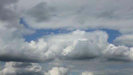 Langsame-Dramatische-Malerische-Schichten-Von-Cumulus-Wolkenformationen,-Die-Auftauchen-Und-Von-Einer-Decke-Vor-Einem-Blauen-Himmel-Verdeckt-Werden