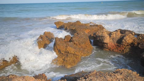 Waves-crashing-on-rocks-at-coastal-sea-shore,-slow-motion