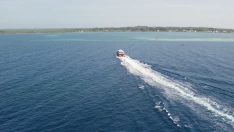 Cruise-ship-sailing-across-The-Caribbean-sea,-arriving-to-the-island-of-Utila,-Honduras---Aerial-view