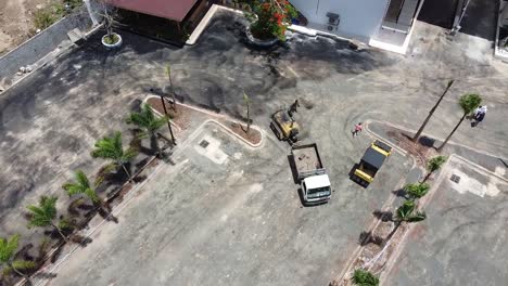 aerial-drone-shot-showing-workers-preparing-the-ground-for-alphalting-commercial-parking-lot,-tourist-zone