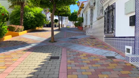 Orangenbäume-Und-Palmen-In-Einer-Typischen-Kleinen-Spanischen-Straße-Mit-Häusern-In-Der-Altstadt-Von-Marbella,-Sonniger-Tag-Und-Blauer-Himmel-In-Spanien,-4k-Nach-Oben-Geneigt