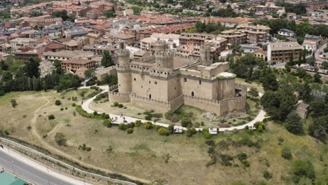 Epic-cinematic-aerial-of-the-New-Castle-of-Manzanares-el-Real-showing-the-historic-landmark-at-the-foot-of-the-Sierra-de-Guadarrama-and-the-surrounding-town-in-the-Community-of-Madrid-Spain