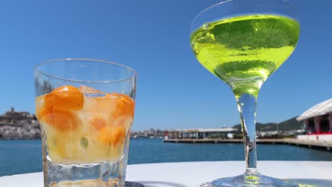slow-downward-tilting-shot-cocktails-in-Ibiza-port-by-the-seaside,-4k-summer-vacation-footage
