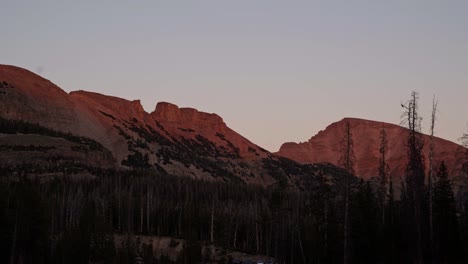 Stunning-remote-high-uinta-Rocky-Mountain-range-in-Utah-in-the-Uinta-National-Forest-during-a-gorgeous-red-vibrant-sunset-with-lone-pine-trees-from-a-campground-on-a-warm-summer-evening