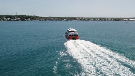 Ferry-in-The-Caribbean-sea,-arriving-to-the-island-of-Utila,-Honduras---Aerial-view