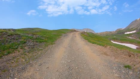 POV-driving-up-Black-Bear-Pass-trail,-driving-on-a-gravel-trail-through-alpine-meadow-in-San-Juan-Mountains-near-Telluride-Colorado