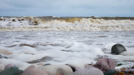Foamy-breaking-ocean-surf-pebble-beach-shoreline-tide-soothing-multicoloured-stones-dolly-right