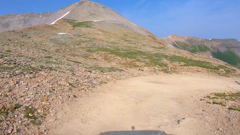 POV-driving-on-Black-Bear-Pass-off-road-trail-while-a-dirt-bike-passes-the-vehicle-around-hairpin-curve-in-San-Juan-mountains-near-Telluride-Colorado:-concepts-of-adventure-and-adrenaline-rush