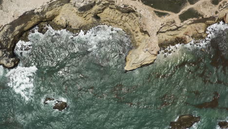 Birdseye-view-looking-down-over-green-seas-and-the-rugged-clifftops-and-old-lighthouse-at-Morrillos-Wildlife-refuge-in-Cabo-Puerto-Rico-on-the-Caribbean-Sea