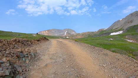 POV-driving-up-Black-Bear-Pass-trail,-driving-on-a-gravel-trail-cut-in-alpine-meadow-in-San-Juan-Mountains-near-Telluride-Colorado