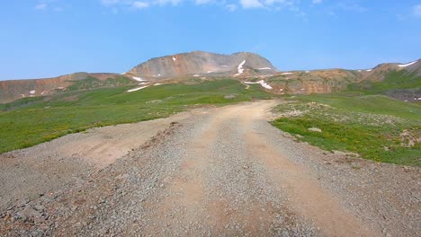 POV-near-Black-Bear-Pass,-driving-on-a-gravel-trail-cut-rocky,-alpine-meadow-in-San-Juan-Mountains-near-Telluride-Colorado