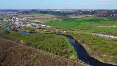 Green-and-brown-tree-and-blue-canal,-aerial-view-of-train-track-in-the-north-of-the-UK-near-Leeds