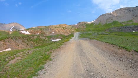 POV-near-Black-Bear-Pass,-driving-on-a-gravel-trail-cut-thru-rocky-hills-and-valleys-in-San-Juan-Mountains-near-Telluride-Colorado
