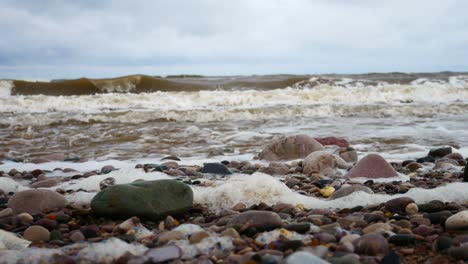 Foamy-breaking-ocean-surf-pebble-beach-shoreline-tide-soothing-multicoloured-stones-right-dolly-shot