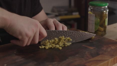 Chopping-pickles-on-wooden-cut-board-with-kitchen-knife
