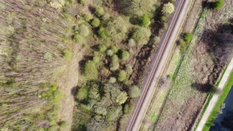 Green-and-brown-tree-and-blue-canal,-aerial-view-of-train-track-in-the-north-of-the-UK