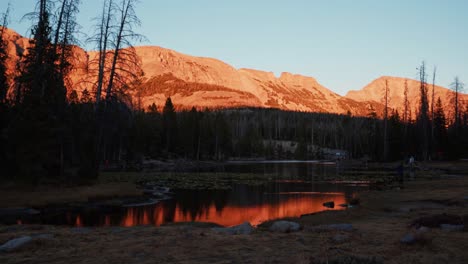 Time-lapse-landscape-shot-of-the-beautiful-Butterfly-Lake-surrounded-by-large-rocky-mountains-and-pine-trees-inside-of-the-Uinta-Wasatch-Cache-National-Forest-in-Utah-during-a-summer-sunset