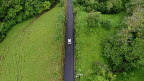 Aerial-panning-up-as-car-travels-down-rural-Central-American-road,-4K