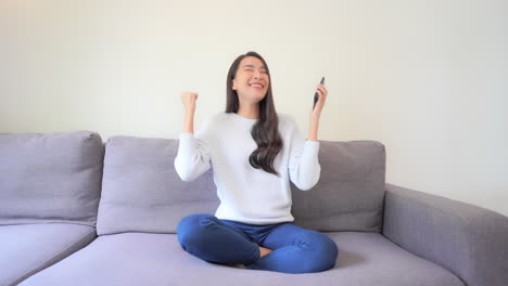 Excited-young-Asian-woman-user-winner-hold-smartphone-feel-amazed-with-good-surprise-social-media-news-mobile-online-bid-app-win-looking-at-cellphone-laughing-celebrating-success-victory-concept