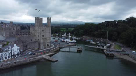 Ancient-Caernarfon-castle-Welsh-harbour-town-aerial-view-medieval-waterfront-landmark-push-in-slow-right