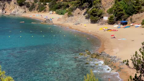 Costa-Brava-beautiful-virgin-transparent-turquoise-waters-lush-vegetation-of-pine-trees-and-rocks-yellow-sand-few-people-Gerona-Catalonia-Mediterranean-Panoramic-views-Tossa-de-Mar-cove-Llevad?